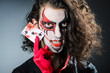 Evil clown with cards in dark room