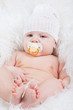 Photo: Portrait of a baby with a pacifier in white hat Portrait of a baby with a pacifier in white hat