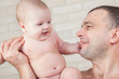 Happy baby and a strong father looking at each other