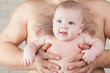 Happy baby on the strong hands of his father