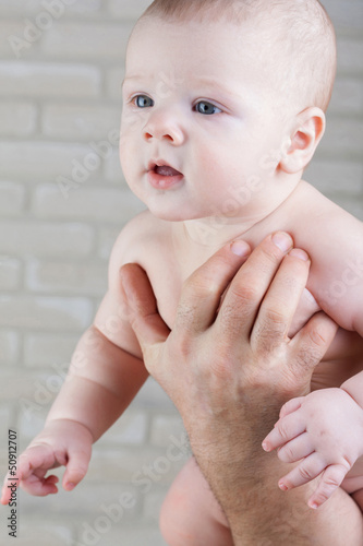 Photo: Baby in the arms of father. Baby looks into the distance. Baby in the arms of father. Baby looks into the distance.