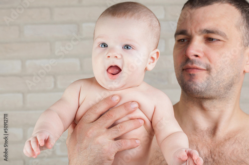 Photo: Naked baby boy in the arms of his father. Naked baby boy in the arms of his father.