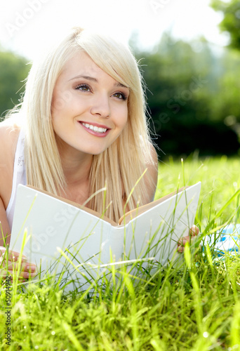 Photo: Young beautiful girl reading a book outdoor Young beautiful girl reading a book outdoor