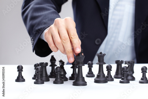 Photo: Business man moving chess figure Business man moving chess figure