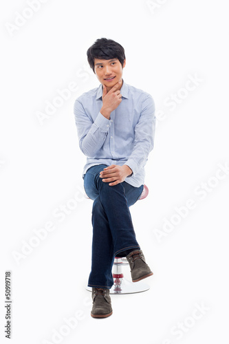 Photo: Young Asian man thinking on the chair. Young Asian man thinking on the chair.