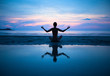 Woman practicing yoga on the beach at sunset