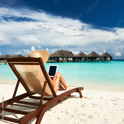 Photo: Young woman with tablet pc at the beach Young woman with tablet pc at the beach