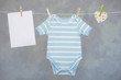 Blue baby goods and blank note hanging on the clothesline
