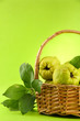 sweet quinces with leaves in basket, on green background