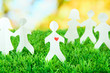Paper people on green grass on bright background
