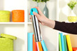 Sprayed air freshener in hand on white shelves background