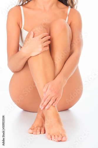 Photo: Woman sitting on the floor touches leg by hand Woman sitting on the floor touches leg by hand