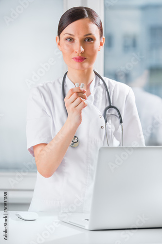 Photo: Young female dentist doctor holding chewing gum and smiling. Den Young female dentist doctor holding chewing gum and smiling. Den