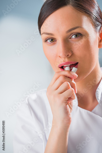 Photo: Young female dentist doctor holding chewing gum and smiling. Den Young female dentist doctor holding chewing gum and smiling. Den
