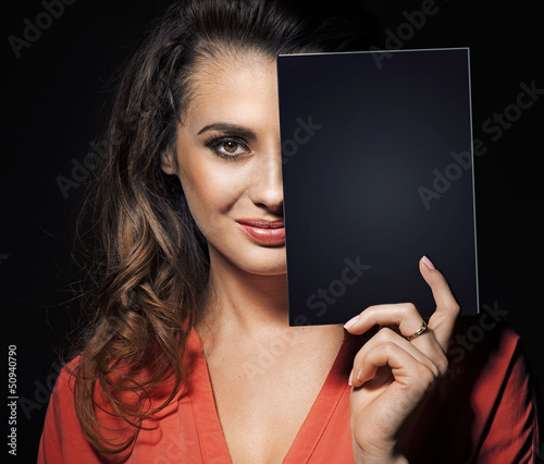 Photo: Beauty brunette hiding half of face behind black panel Beauty brunette hiding half of face behind black panel