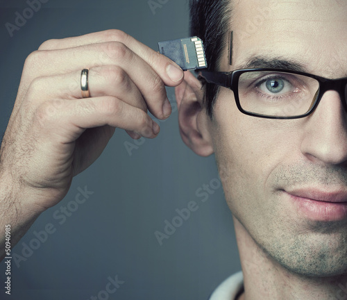 Photo: Young man inserting a SD Card into his head Young man inserting a SD Card into his head