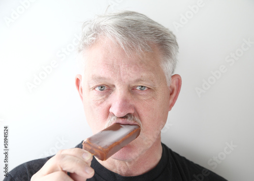 Photo: man eats chocolate ice cream bar man eats chocolate ice cream bar