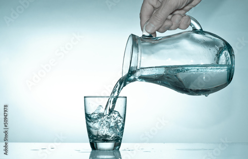 Photo: Hand fills a glass with water from a glass pitcher Hand fills a glass with water from a glass pitcher