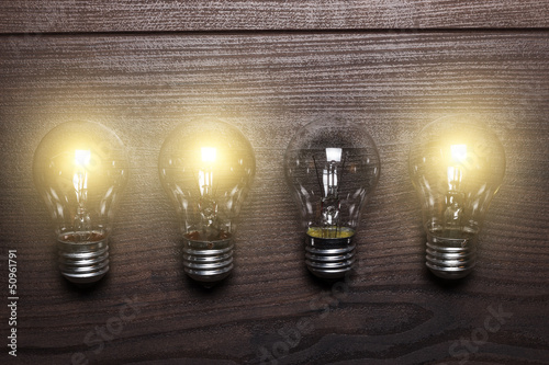 Photo: glowing bulbs weak link concept on wooden background glowing bulbs weak link concept on wooden background