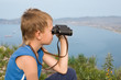 Photo: Boy looking through binoculars of the mountain. Boy looking through binoculars of the mountain.