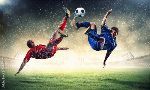 Photo: two football players striking the ball two football players striking the ball