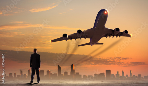 Photo: Businessman looking at airplane in sky Businessman looking at airplane in sky