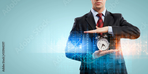 Photo: Business man holding alarmclock Business man holding alarmclock
