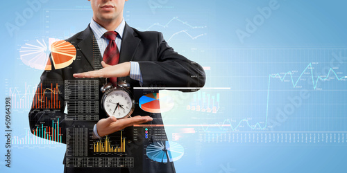 Photo: Business man holding alarmclock Business man holding alarmclock