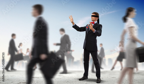 Photo: Businessman in blindfold among group of people Businessman in blindfold among group of people