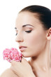 The beautiful woman holds a flower of a carnation at the face