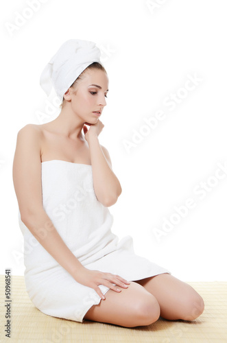 Photo: The beautiful woman in a towel on bamboo rug. SPA concept. The beautiful woman in a towel on bamboo rug. SPA concept.
