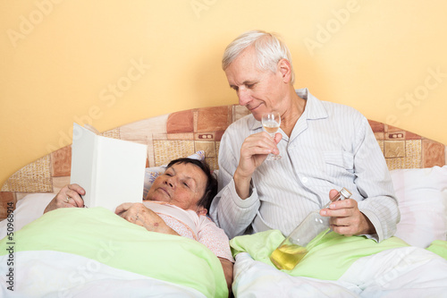 Photo: Funny seniors relax with alcohol in bed Funny seniors relax with alcohol in bed