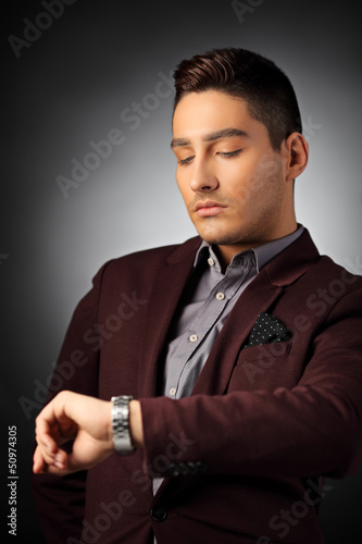 Photo: Handsome fashionable guy checking the time on his watch Handsome fashionable guy checking the time on his watch