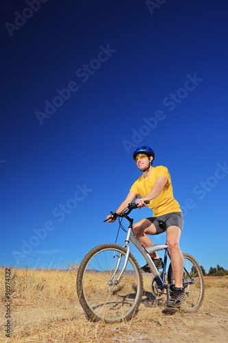Photo: A young male with yellow shirt and helmet riding a mountain bike A young male with yellow shirt and helmet riding a mountain bike