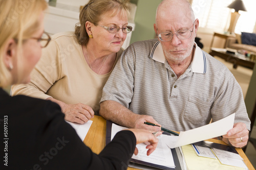 Photo: Senior Adult Couple Going Over Papers in Their Home with Agent Senior Adult Couple Going Over Papers in Their Home with Agent