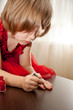 Photo : Little girl in a red dress painted nails with nail polish Little girl in a red dress painted nails with nail polish