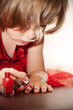 Photo : Little girl in a red dress painted nails with nail polish Little girl in a red dress painted nails with nail polish