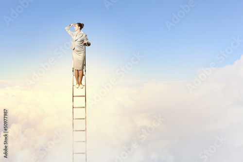 Photo: Businesswoman standing on ladder Businesswoman standing on ladder
