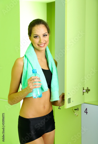 Photo: Young girl in locker room with towel and bottle of water Young girl in locker room with towel and bottle of water