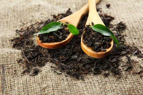 Photo: Dry tea with green leaves in wooden spoons, on burlap Dry tea with green leaves in wooden spoons, on burlap