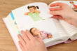 Photos in hands and photo album on wooden table