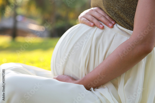 Photo: Close up pregnant woman in the park at the morning Close up pregnant woman in the park at the morning