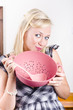 Cute cook holding pink sieve when cooking at home