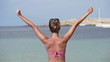 Woman on beach raising hands to the sky, super slow motion