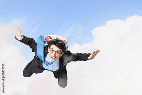 Photo: Young businessman flying with parachute on back Young businessman flying with parachute on back