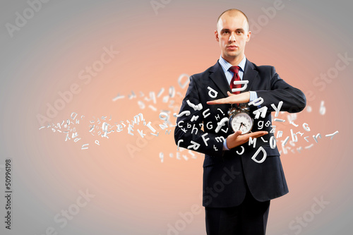 Photo: Business man holding alarmclock Business man holding alarmclock