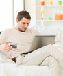 young man with laptop and credit card at home