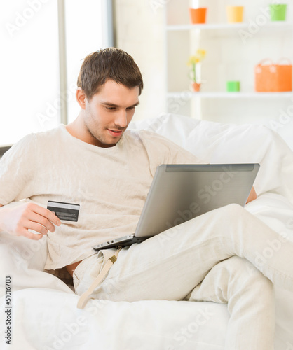 Photo: young man with laptop and credit card at home young man with laptop and credit card at home