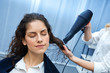 stylist drying woman hair in salon