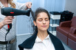stylist drying woman hair in salon
